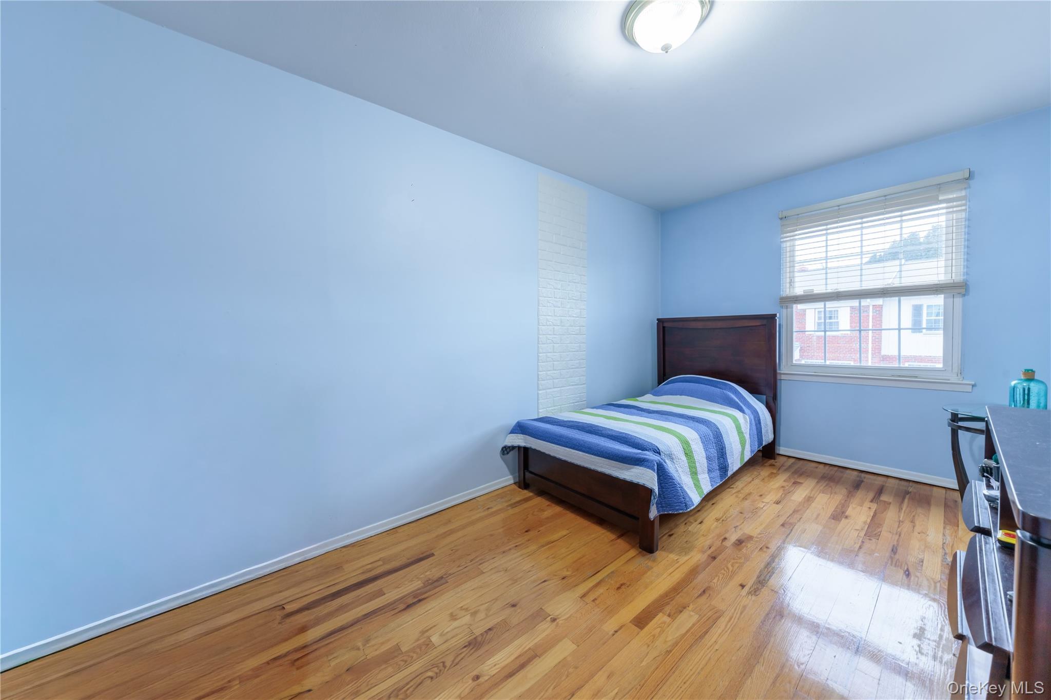 678 Front Street, Unit E Hempstead, NY 11550 - Photo 17 of 22 a bedroom with a bed and wooden floor