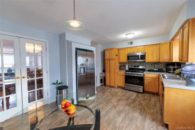 a kitchen with stainless steel appliances kitchen island granite countertop a stove top oven a sink dishwasher a dining table and chairs with wooden floor