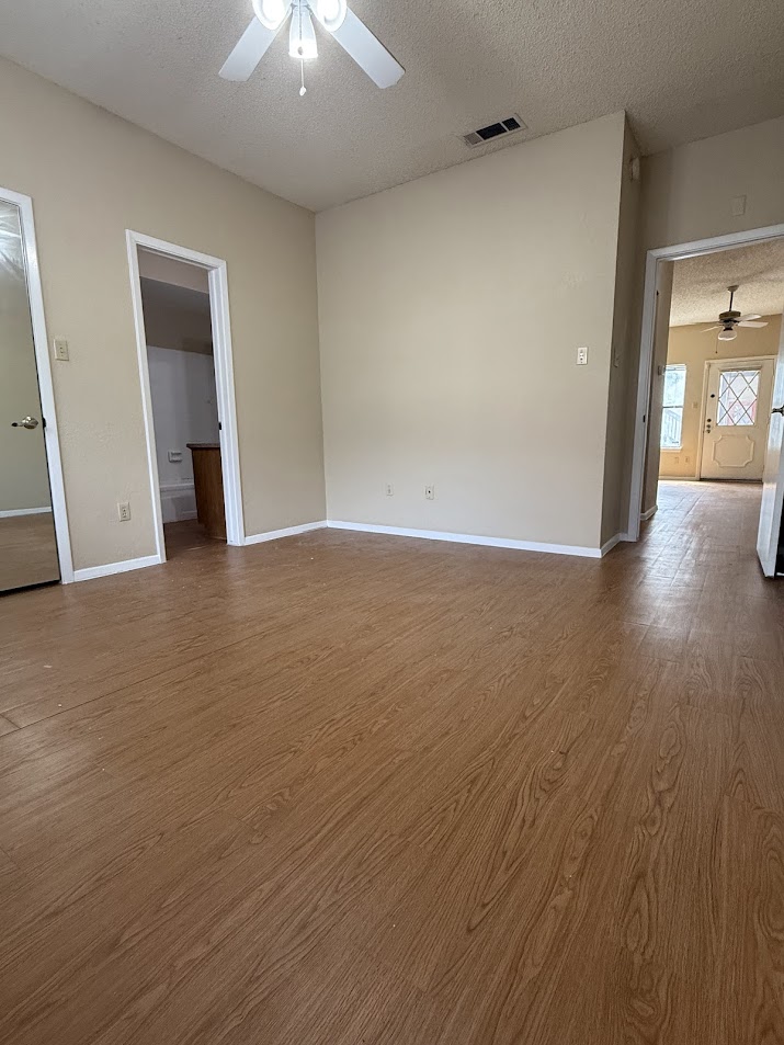 806 West 24th Street, Unit 223 Austin, TX 78705 - Photo 12 of 16 Unfurnished room featuring visible vents, wood finished floors, a textured ceiling, and ceiling fan