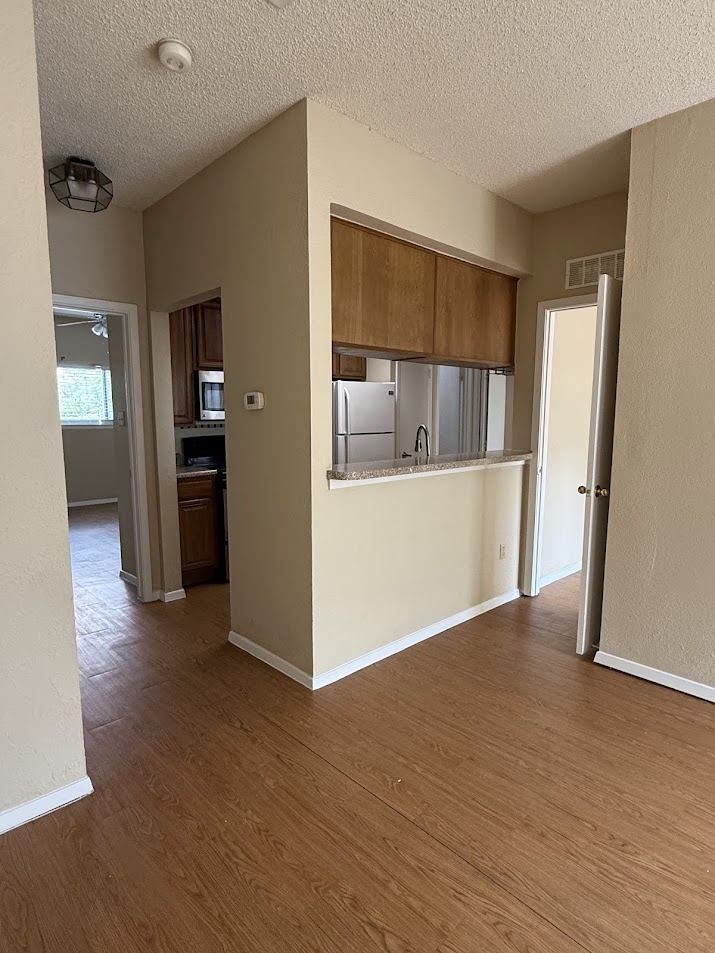 806 West 24th Street, Unit 223 Austin, TX 78705 - Photo 4 of 16 Kitchen with stainless steel microwave, freestanding refrigerator, visible vents, and dark wood finished floors