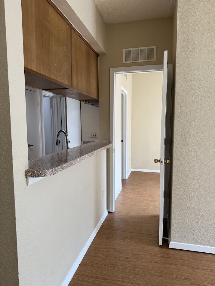 806 West 24th Street, Unit 223 Austin, TX 78705 - Photo 5 of 16 Kitchen with brown cabinets, baseboards, visible vents, and dark wood-style floors