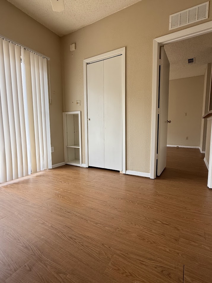 806 West 24th Street, Unit 223 Austin, TX 78705 - Photo 6 of 16 Unfurnished bedroom featuring a textured ceiling, wood finished floors, visible vents, and baseboards