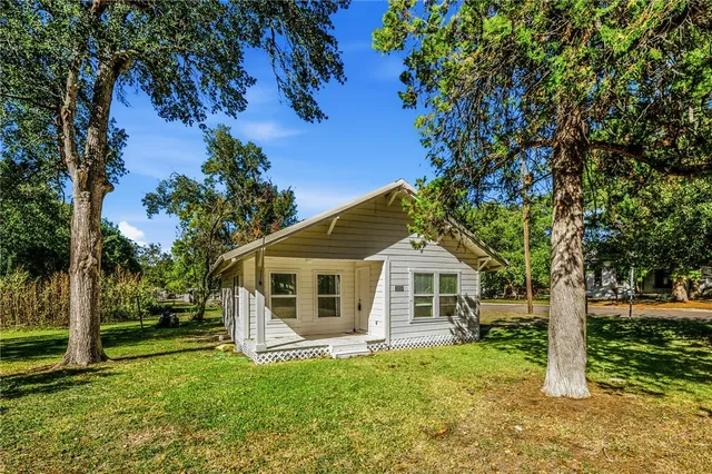 a white house with a big yard and large trees