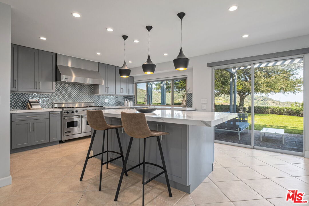 2526 Cordelia Road Los Angeles, CA 90049 - Photo 23 of 35 a kitchen with stainless steel appliances granite countertop a stove a sink a oven a dining table and chairs