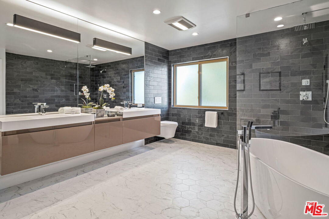 2526 Cordelia Road Los Angeles, CA 90049 - Photo 30 of 35 a bathroom with a double vanity sink large mirror and a bathtub