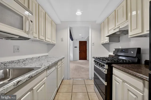 a kitchen with granite countertop a stove sink and cabinets