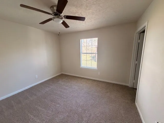 an empty room with a window and a fan
