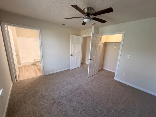 an empty room with windows and a ceiling fan