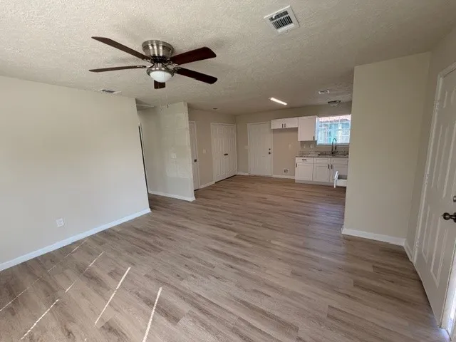 an empty room with wooden floor and a ceiling fan