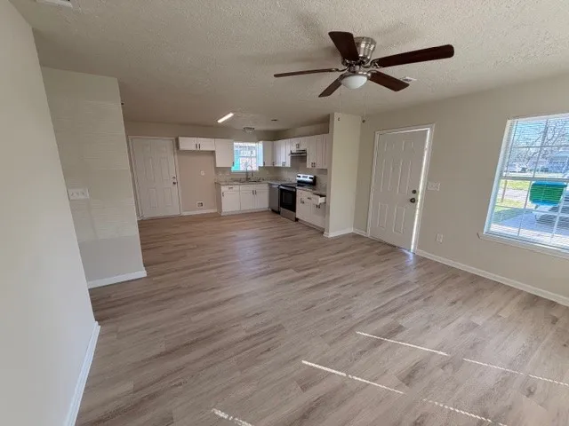a view of empty room with wooden floor and ceiling fan