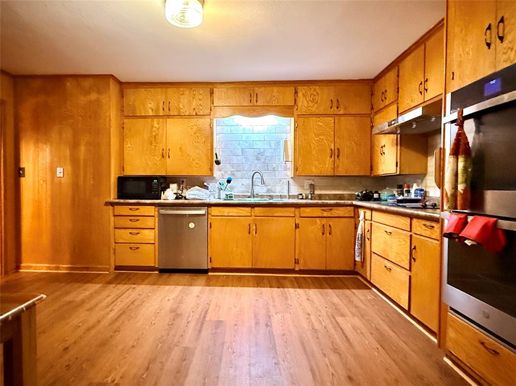 429 Agnes Avenue Marlin, TX 76661 - Photo 11 of 28 a large kitchen with stainless steel appliances granite countertop a stove a sink dishwasher and white cabinets with wooden floor