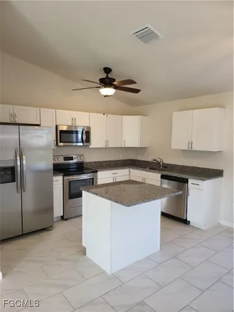 a kitchen with stainless steel appliances granite countertop a sink a stove a refrigerator and island