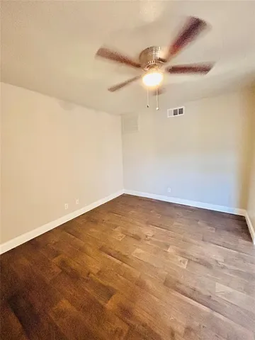 a view of a hallway with wooden floor and a bathroom