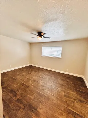 an empty room with a ceiling fan and window