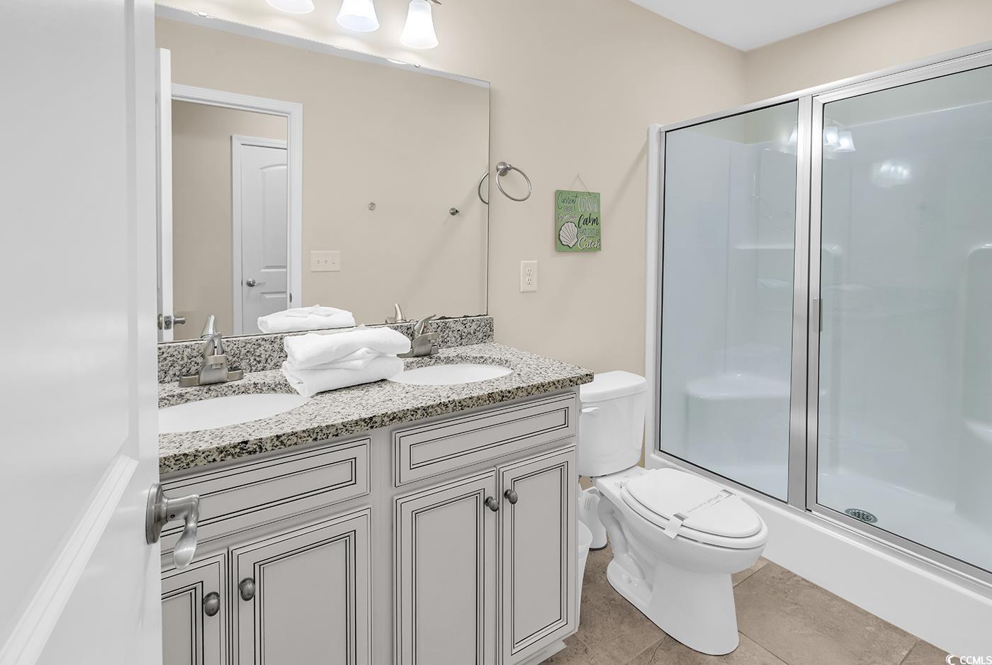 117 B 16th Avenue South Surfside Beach, SC 29575 - Photo 29 of 40 Full bathroom featuring a shower stall, double vanity, and light tile patterned floors
