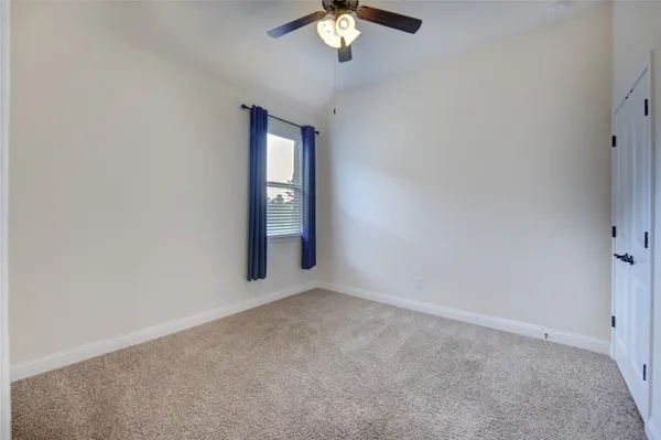 an empty room with chandelier fan and windows
