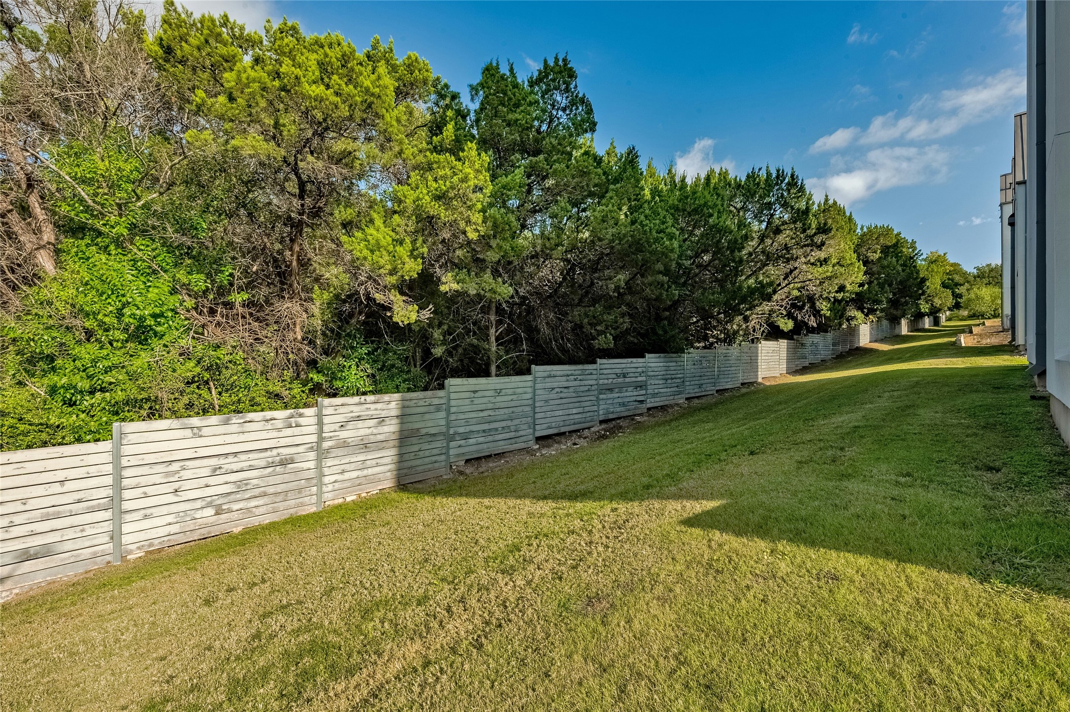 2518 Sutherland Street Austin, TX 78746 - Photo 29 of 30 A well-maintained lawn extends along a sturdy fence, offering a private green space.