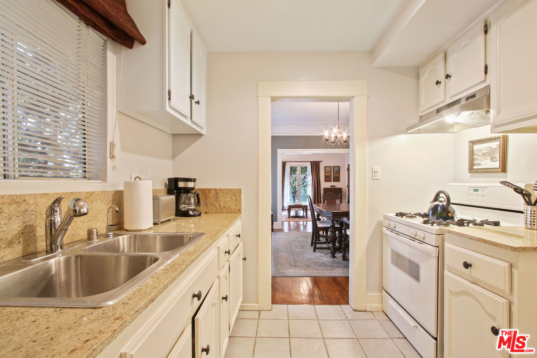 619 North Plymouth Boulevard, Unit 619 Los Angeles, CA 90004 - Photo 8 of 15 a kitchen with stainless steel appliances white cabinets a sink a stove a washer and dryer
