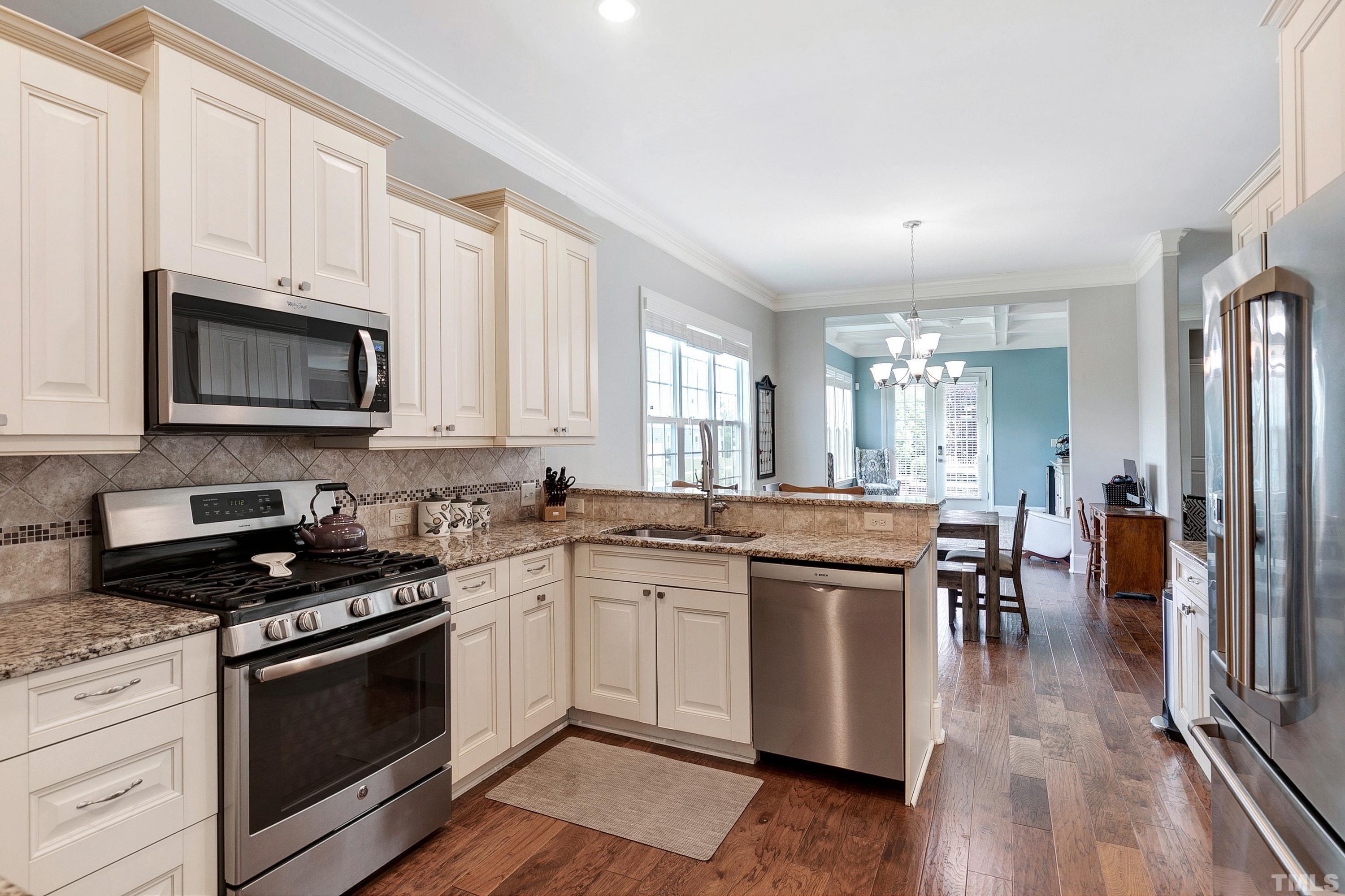 1001 Ambergate Station Apex, NC 27502 - Photo 11 of 49 a kitchen with granite countertop stainless steel appliances a stove cabinets and wooden floor