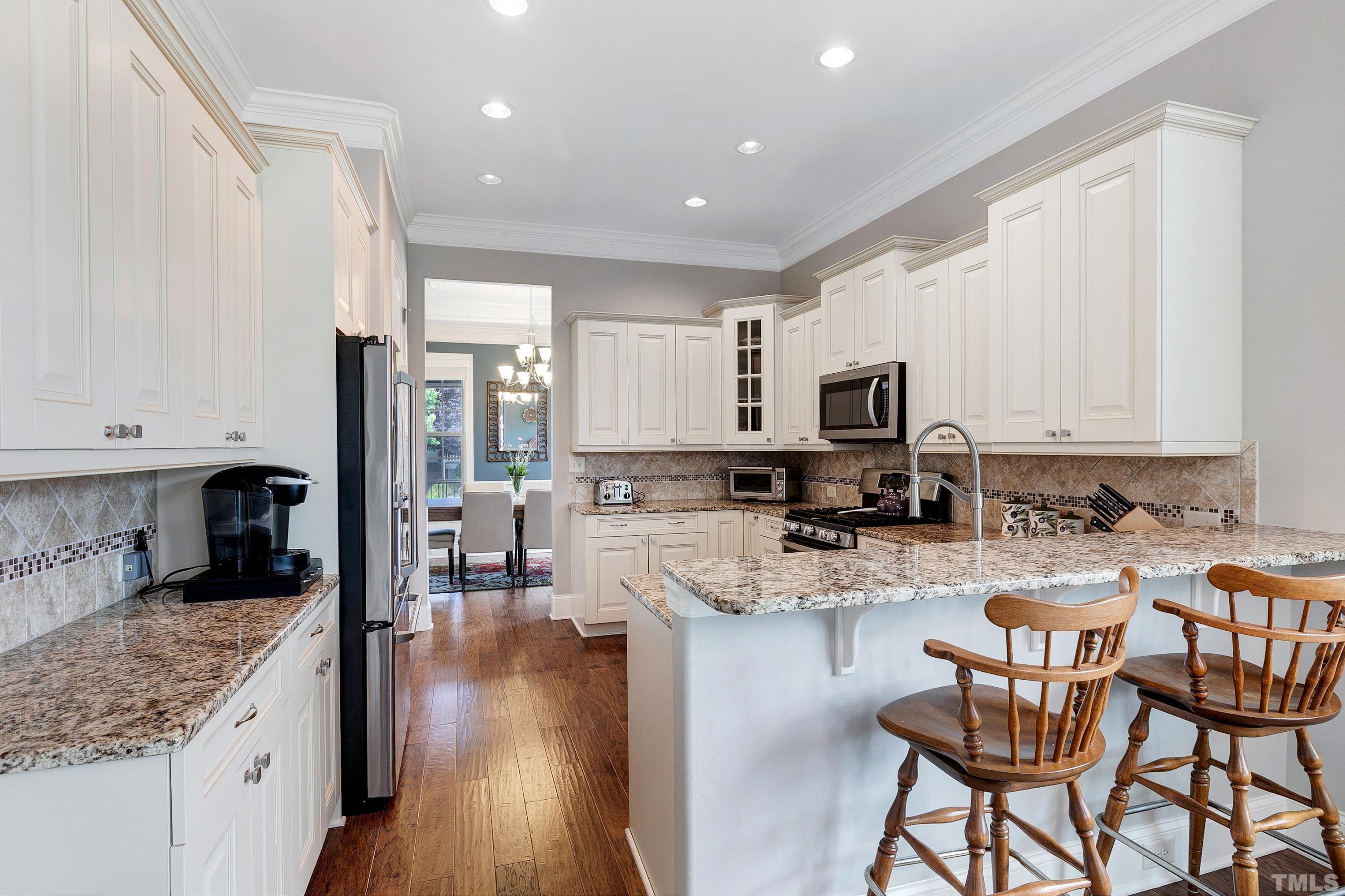 1001 Ambergate Station Apex, NC 27502 - Photo 9 of 49 a kitchen with stainless steel appliances granite countertop a stove top oven a sink a refrigerator white cabinets and wooden floor