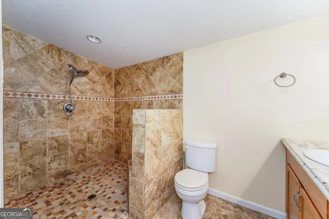 a bathroom with a granite countertop toilet and a shower