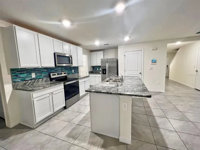 a kitchen with stainless steel appliances granite countertop a sink stove and cabinets