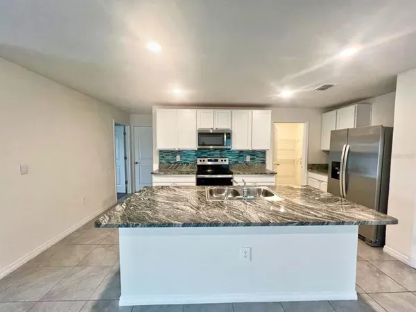 a kitchen with stainless steel appliances granite countertop a sink refrigerator and microwave