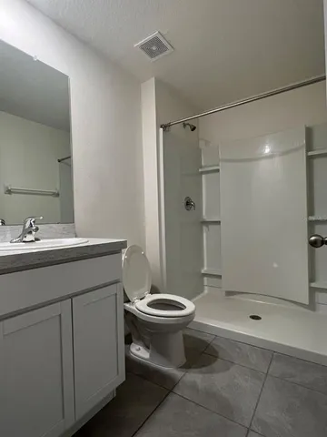 a bathroom with a shower sink vanity and toilet