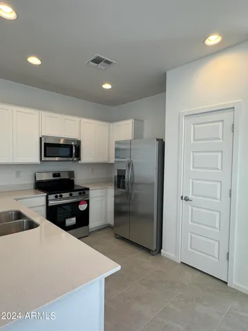 a kitchen with granite countertop a refrigerator and a stove top oven