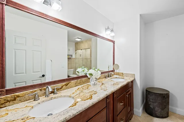 a bathroom with a granite countertop double vanity and a mirror