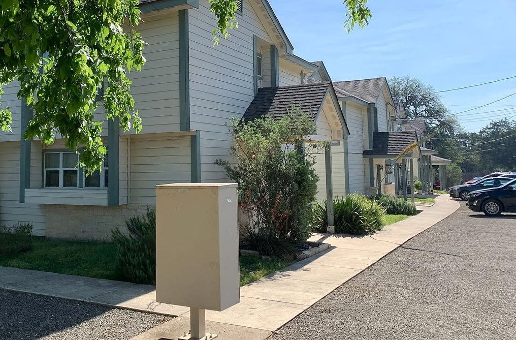 a view of a white house with a small yard and a large tree