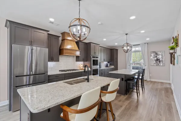 a kitchen with stainless steel appliances granite countertop a kitchen island a table and chairs in it