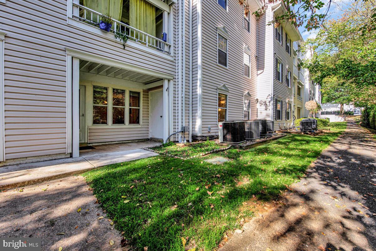 20334 Beaconfield Terrace, Unit 2 Germantown, MD 20874 - Photo 23 of 24 a view of a house with a small yard and a large tree in the background