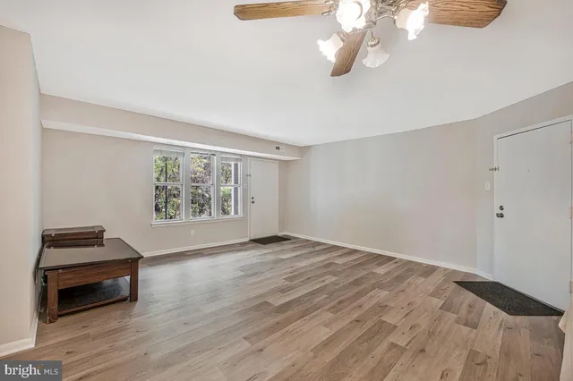 a view of an empty room with wooden floor and a window