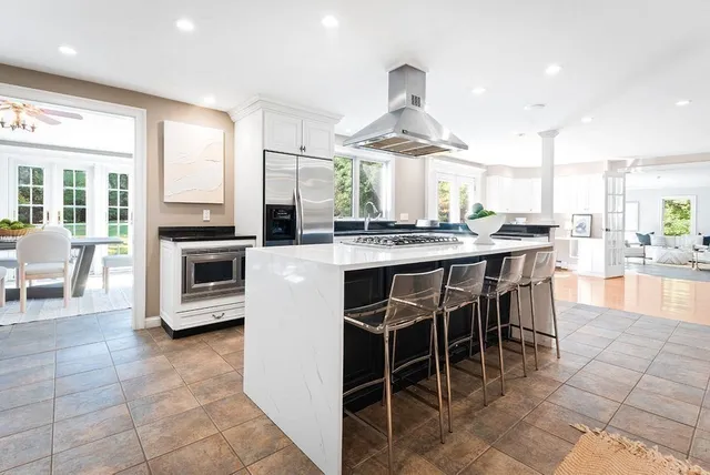 a kitchen with stainless steel appliances a stove a sink a oven a dining table and chairs