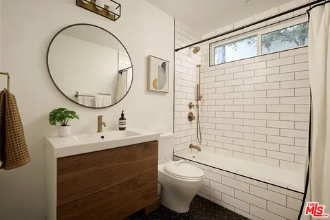 a bathroom with a toilet sink vanity tub and mirror