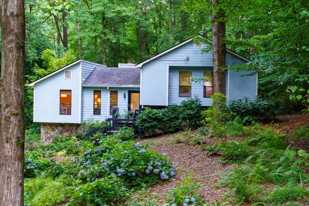 a view of a house with lots of plants and large trees