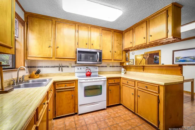a kitchen with stainless steel appliances granite countertop a sink a stove and a refrigerator