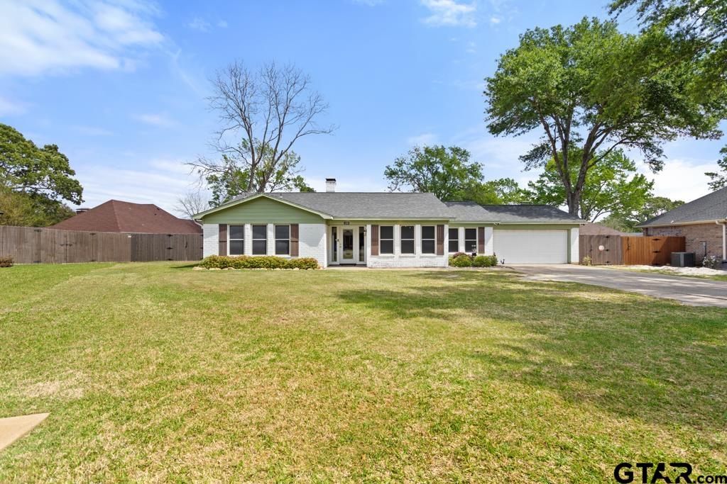a front view of house with yard and trees in the background