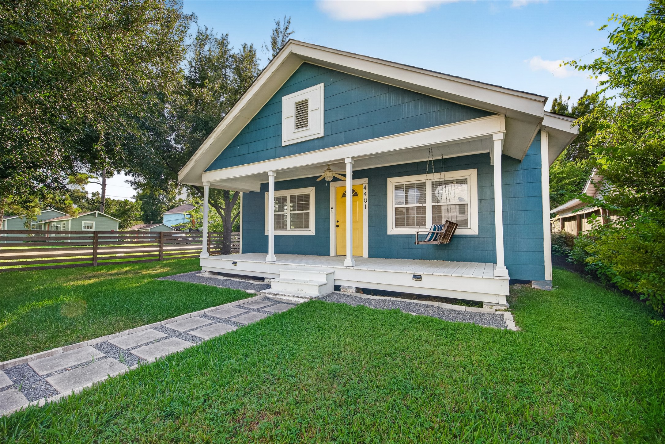 4401 Hain Street Houston, TX 77009 - Photo 2 of 22 An angled exterior view highlights the home’s fenced corner lot, covered front porch, mature shade tree, and welcoming approach to the yellow front door.
