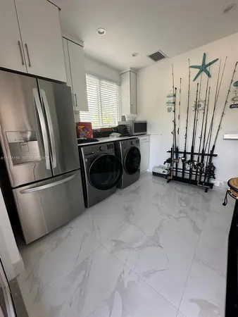 a kitchen with stainless steel appliances a refrigerator a sink a stove a refrigerator a washer dryer and white cabinets