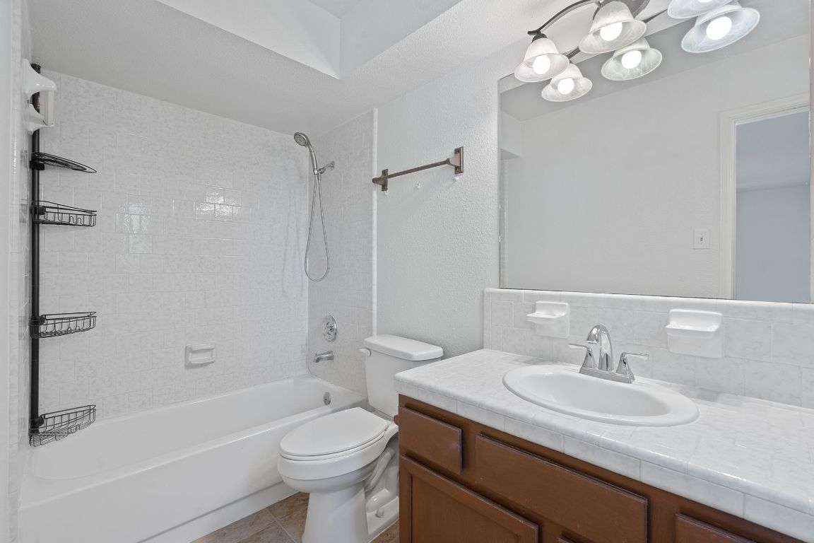 130 Meyers Road Buda, TX 78610 - Photo 13 of 35 a bathroom with a granite countertop sink a toilet a mirror and shower