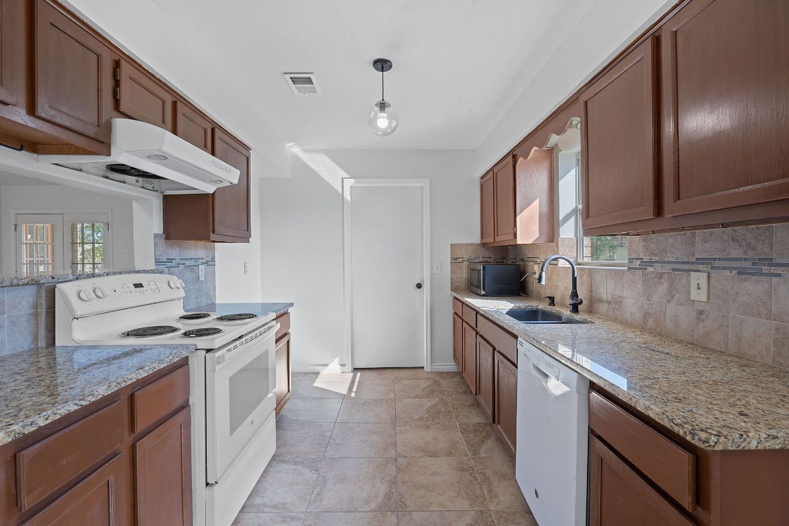 130 Meyers Road Buda, TX 78610 - Photo 8 of 35 a kitchen with stainless steel appliances granite countertop a stove sink and cabinets