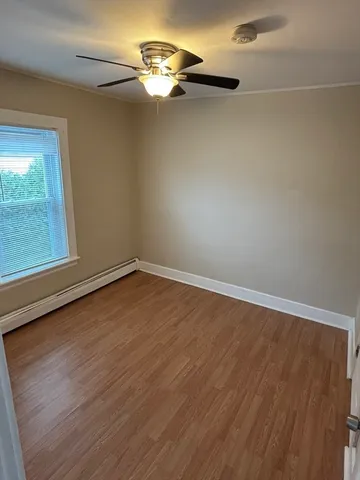 an empty room with wooden floor chandelier fan and windows