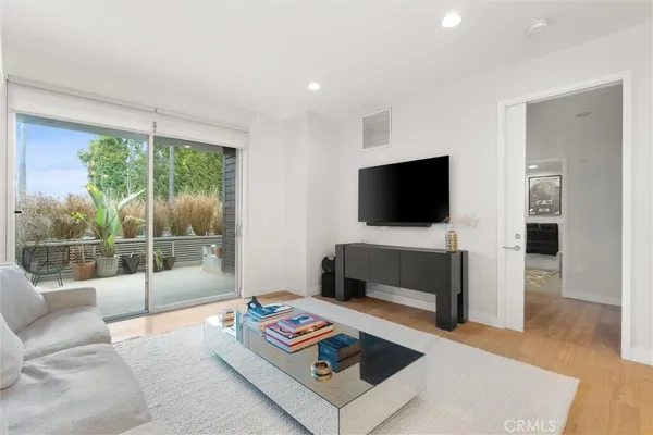 a living room with furniture a flat screen tv and a floor to ceiling window