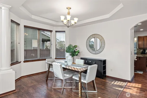 a dining room with chandelier and wooden floor