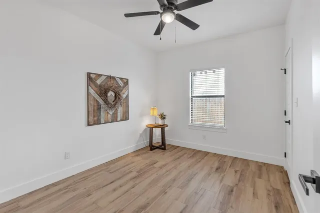 a view of an empty room with a window and wooden floor