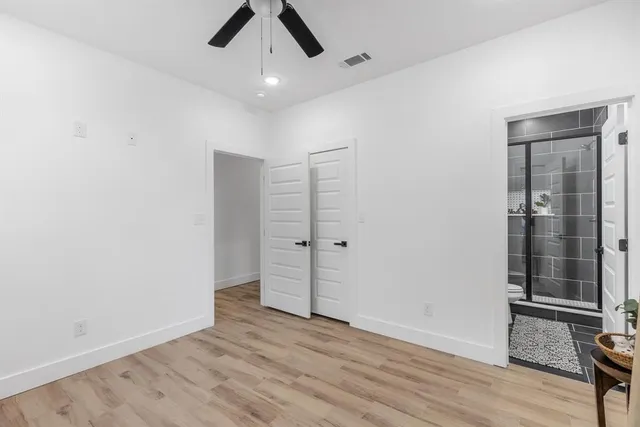 an empty room with wooden floor cabinet and windows