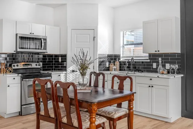 a kitchen with stainless steel appliances granite countertop a table chairs and a sink
