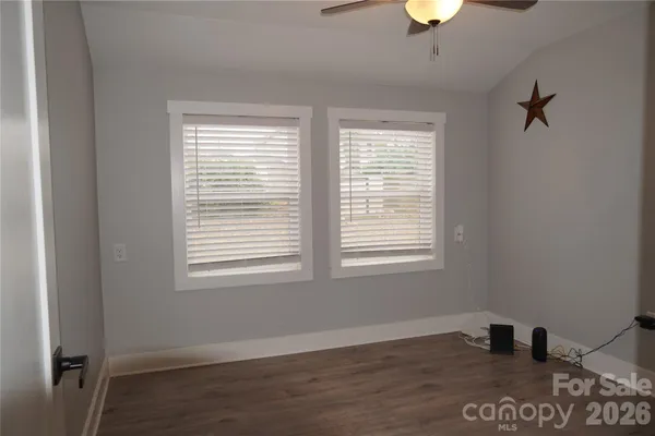 a view of an empty room with a window and wooden floor